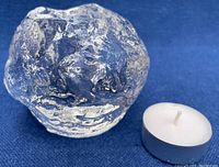 Clear textured crystal snowball candle holder with included white tealight candle shown against blue background.