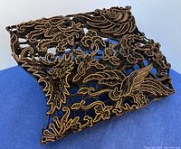 Top angled view of copper pattern stamp showing intricate floral and bird designs in relief on a copper plate.