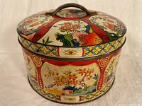 Front angled view showing lid with handle and floral pattern with gold highlights on round tin.