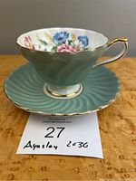 Side view of Aynsley jadite green teacup with floral interior on matching saucer