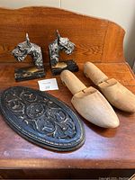 Overall view of cast metal Scottie dog bookends, wooden shoe inserts, and carved wood wall decor on a wooden surface
