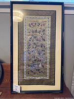 Framed full view of the embroidered tapestry showing 100 children