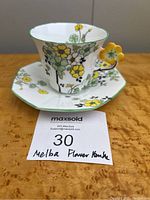Teacup and saucer on wooden surface with seller's lot card