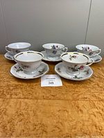 Five teacups and saucers arranged showing Wawel and Jarolina sets with floral patterns and gold accent trim.