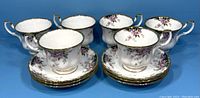 Set of six Royal Albert Balmoral pattern teacups and saucers arranged in a group, showing floral design and gold trim.
