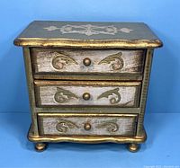 Front view of the Italian Florentine musical jewelry box showing 3 drawers and decorative floral motifs with gold accents.