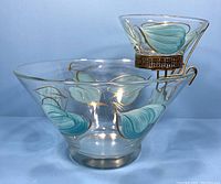 Chip and dip set showing large bowl with small dip bowl and metal stand against light blue background.