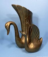 Front view showing large brass swan vase with extended wing and baby swan beside it