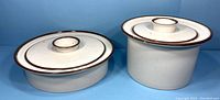 Pair of stoneware casserole pots with lids side by side showing size difference and shape