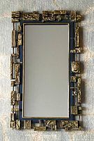 Full view of the rectangular mirror showing the frame and its gold-tone textured geometric embellishments.