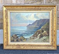 Framed oil on canvas coastal landscape painting showing the entire artwork including frame against outdoor background.