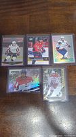 Five Alex Ovechkin hockey cards arranged on wooden surface. Cards vary in design and feature Ovechkin in different uniforms and action poses.
