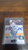 Front view of Auston Matthews hockey card in protective case showing player in action and team logo.