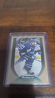 Photo of Auston Matthews hockey card from Parkhurst series in a clear plastic protective case on a wood surface.