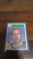 Close-up photo of Bart Starr NFL trading card in plastic protective case on wooden table.