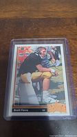 Photo of Brett Favre rookie card in protective case on wooden surface.
