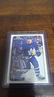 Photo showing the Mitch Marner hockey trading card in a protective sleeve, featuring the player in Toronto Maple Leafs uniform, 'MVP' series, with a silver autograph graphic.