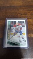 Photo shows a Nick Suzuki rookie hockey card in a protective plastic case, with the player in a Montreal Canadiens uniform and the card branded 'Score'.