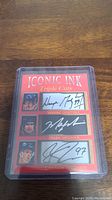 Photo of a sports memorabilia card titled 'ICONIC INK Triple Cuts' showing facsimile autographs of Wayne Gretzky, Mark Messier, and Connor McDavid in protective plastic casing.