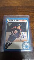 Trading card showing Wayne Gretzky in Edmonton Oilers uniform with facsimile autograph on front. Card is in protective hard plastic holder.