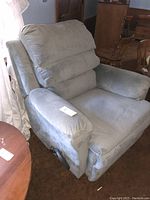 Blue-gray fabric swivel rocking reclining chair shown from the front-left angle. Manual lever visible on the chair side.