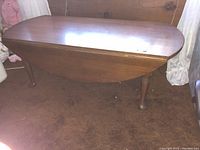 Side view of the oval drop leaf coffee table showing the rounded Queen Anne legs and drop leaf detail.