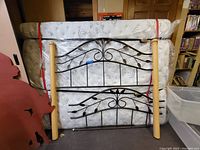 View showing queen metal headboard and footboard with wooden posts, mattress secured behind.