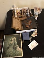 Photo of all religious items on table showing cross, angel figurines, framed prayers, praying hands plaque and portrait of Jesus Christ.