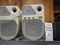 Pair of white Reveal brand speakers with grey mesh and built-in control knobs
