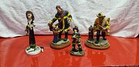 Four firefighter-themed figurines arranged on a red surface, showing detailed firefighter uniforms and scene bases