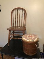 Full view of Windsor style wooden chair with wooden bucket stool with floral cushioned top beside it.