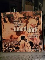 Laser disc boxed set of Woodstock, shown with sepia-toned historic event imagery and text noting 40 extra minutes of never-before-seen footage. The packaging states '3 Days of Peace & Music The Director's Cut'.