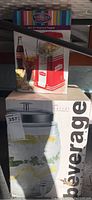 Photo showing boxed Nostalgia Electrics Hot Air Popcorn Popper with Coca Cola design and boxed beverage dispenser beneath.