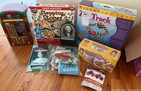 Photo showing small jukebox radio, multiple boxed toys and craft kits including Stepping Stones, Zip Track, Precious Mugs, Scrabble, balloons and ziploc bags of pieces.