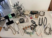 Full view of the collection showing multiple costume jewelry necklaces, bracelets, display stands, and two jewelry boxes on a white table.