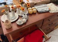 Wide view of wooden sideboard showing floral centerpieces, candles, table linens and wine bottle holder.