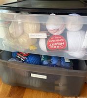 Two translucent plastic drawers filled with yarn skeins, top drawer containing white yarns, bottom drawer containing blue yarns.