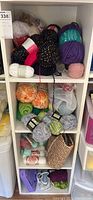 Shelf section containing various yarn skeins in multiple colors and textures.