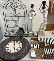 Wide shot showing standing metal clock, two figurines, art glass plate, and candle holder inside a box.