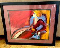 Front view of framed Linda Le Kinff art print depicting a seated woman with blonde hair in a red dress holding a flower.
