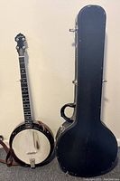 Banjo and closed hard shell case side by side against wall