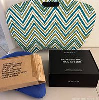 Padded lap desk with chevron pattern in background, a blue recliner lever extender in its box, and a MOROVAN Professional Nail System black box arranged in front.