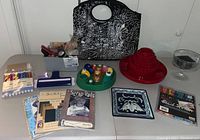 Full view of various art and crafting supplies including paper punches, scrap pads, paints, markers, display stands, and storage bowls on table.