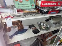 Contents of two shelves with baking molds, cake decorating set, and kitchenware including ice cream maker.