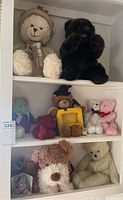 Shelf with two large teddy bears, various small teddy bears, and a plush dog.