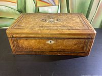 Full view of the rectangular antique wooden traveling secretary box with burl wood veneer and inlaid decorative design on top.