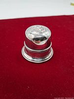 Closed vintage Birks silverplate ring box on red surface, showing aged patina and wear.