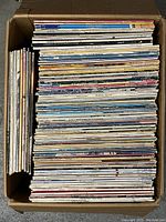 Overhead view of a box filled with neatly stacked vintage vinyl records in various colored sleeves.