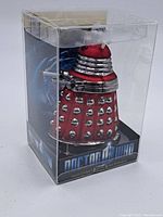 Red Dalek glass ornament in clear plastic package showing side details and base with Doctor Who branding.