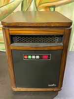 Full front view of the Duraflame electric heater in a wooden cabinet showing the air vent and control panel area.